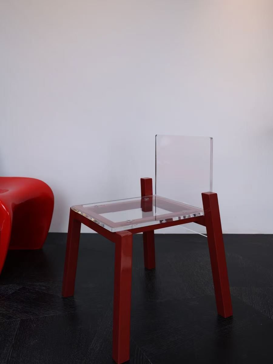 Float Chair with red legs on a dark floor, beside a red chair